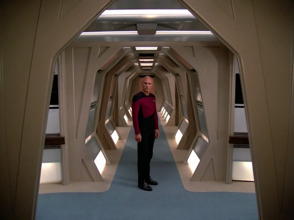 TNG; "Encounter at Farpoint"; an #iconic shot of Picard standing at the meeting point of two corridors and looking into the camera, framed by a bulkhead; the corridor extends 50 feet behind him to a turbolift door