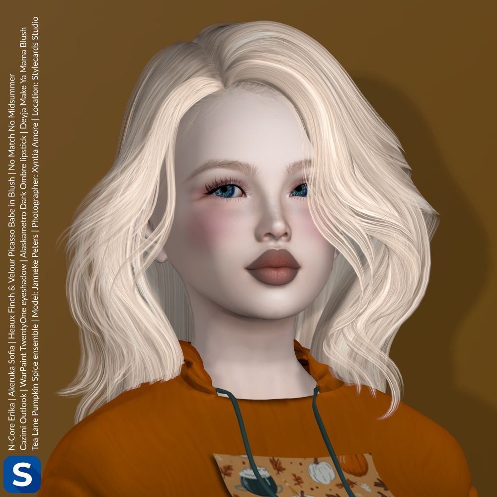 A headshot of Janneke Peters standing in front of a  caramel-colored backdrop. She is wearing a festive orange hoodie with some pumpkin decorations on the front. She has long blonde hair, a hint of eyeshadow,  some blush on her cheeks, and a brownish lipstick.