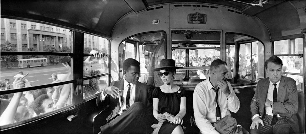 Panoramic shot of the four sitting next to each other on a long seat on a bus