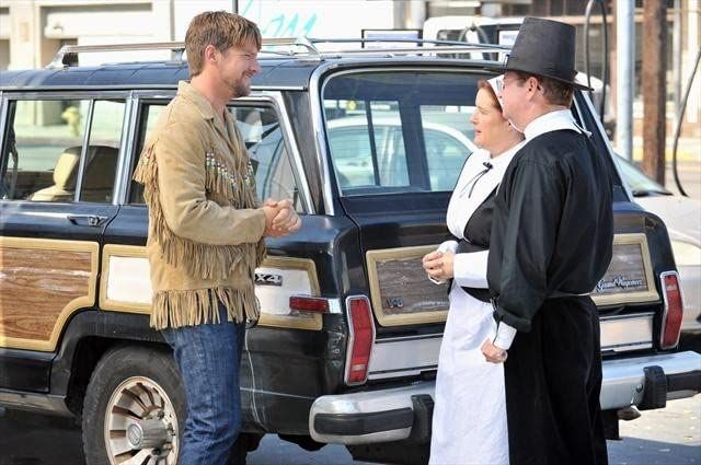 Dave Rose, in his fringed jacket, talks at a gas station with a couple dressed as Pilgrims