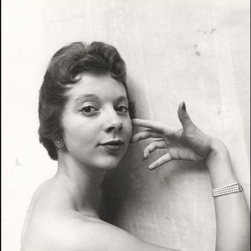 Massey with bare shoulders, her graceful hand up to her face