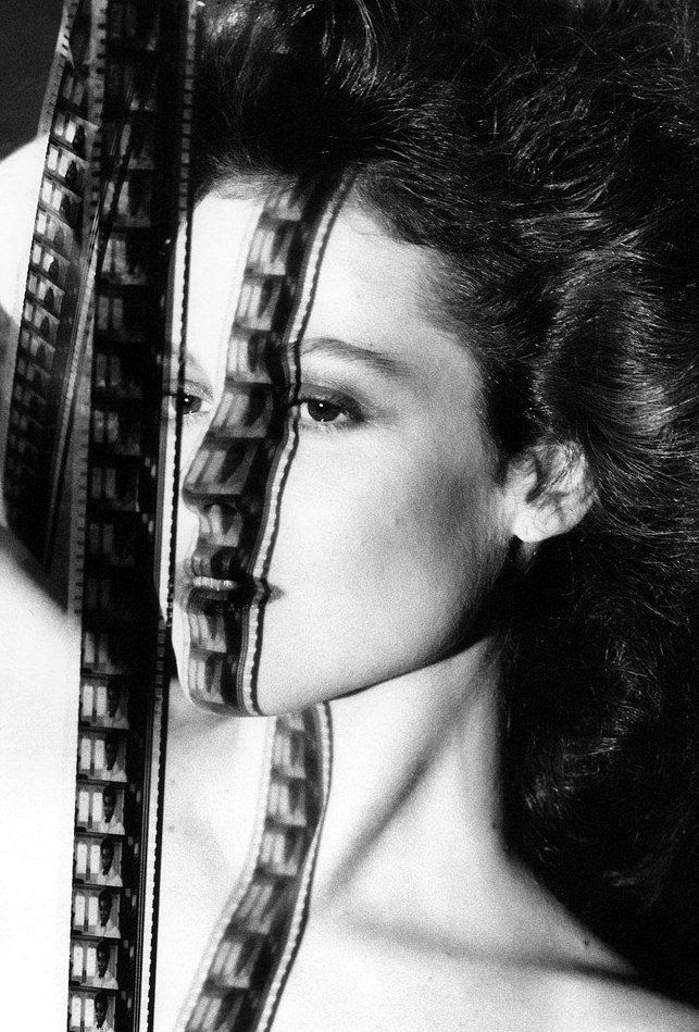 Weaver holds up movie film in front of her; the shadow falls over her face.