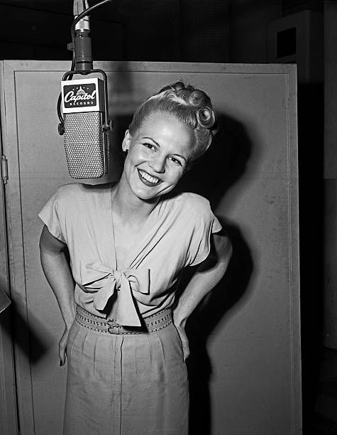 A smiling Lee in a recording studio, with a very large Capitol microphone.