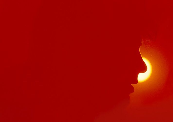 A photo in red; Delon is seen in a profile silhouette against a yellow light.