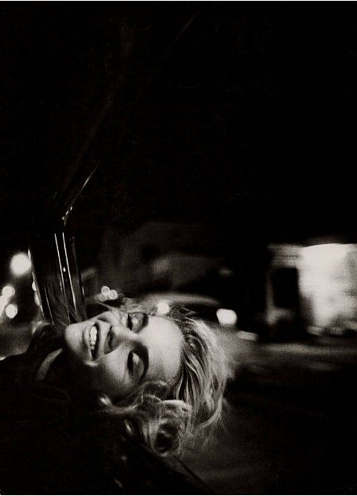Weld puts her head back & smiles, eyes closed, driving in a car at night.