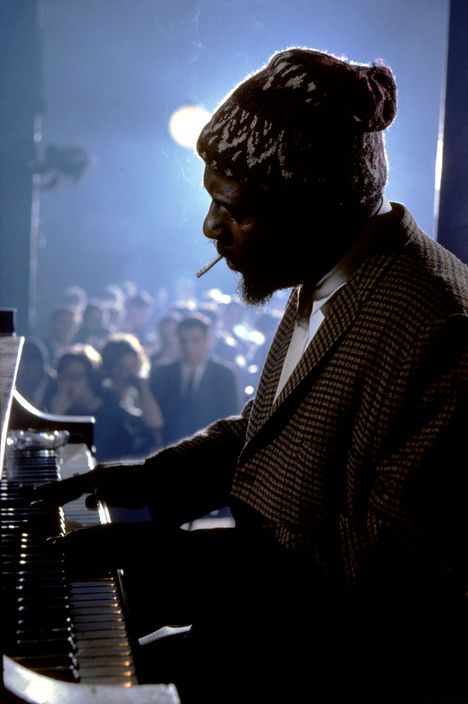 Monk in his trademark knit hat, smoking a cigarette at the piano