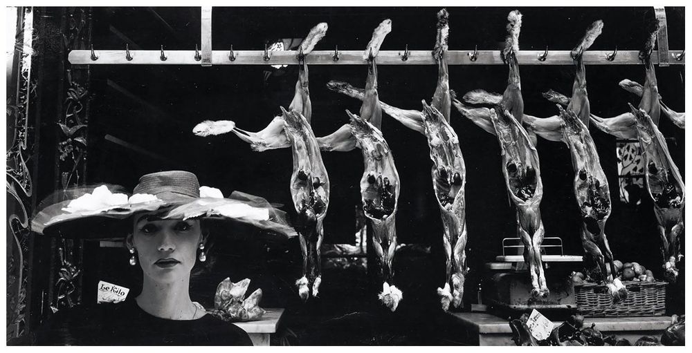 A model in a broad-brimmed hat poses in front of dressed rabbit carcases at the meat market.