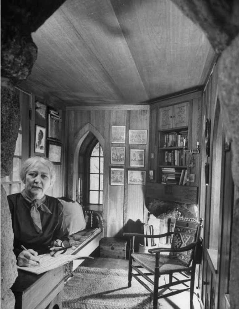 Una writes in the foreground. In the background, a wonderful room with elaborate wordwork.