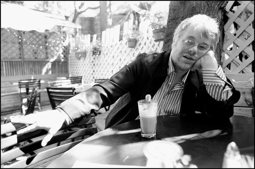 Black & white shot of Hoffman having a drink in an outdoor restaurant
