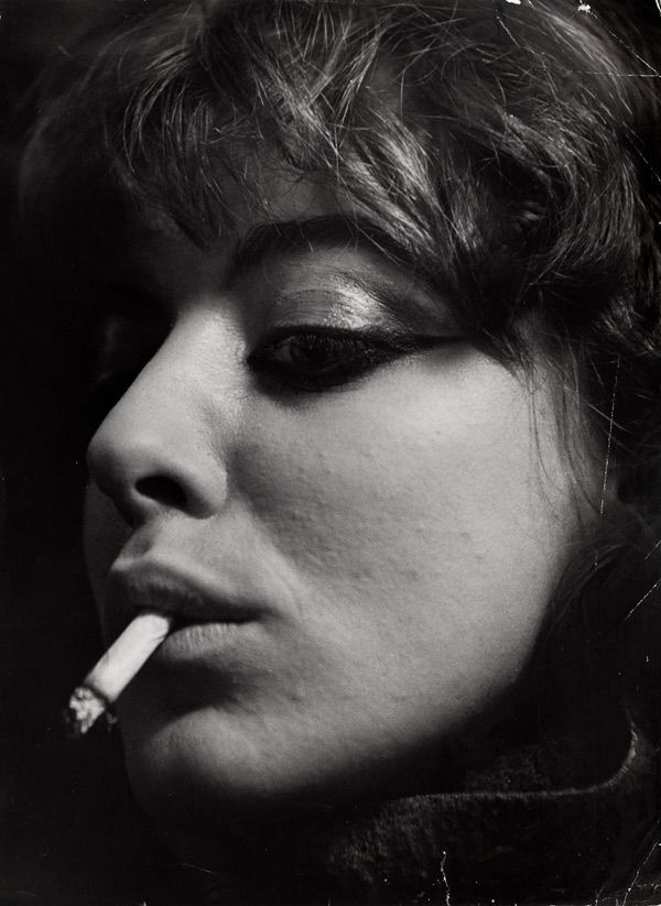 Closeup of Myers with her eyes down-turned, and a cigarette hanging from her mouth.