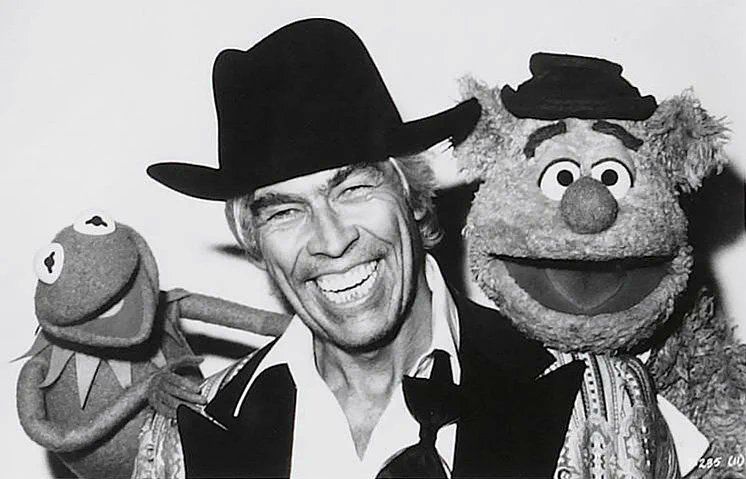 A smiling Coburn, wearing a cowboy hat, between Kermit the Frog & Fozzie Bear.