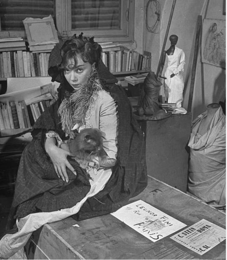 Fini poses with a long-haired cat on her lap.