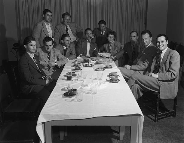 Two rows of photographers pose around a table.
