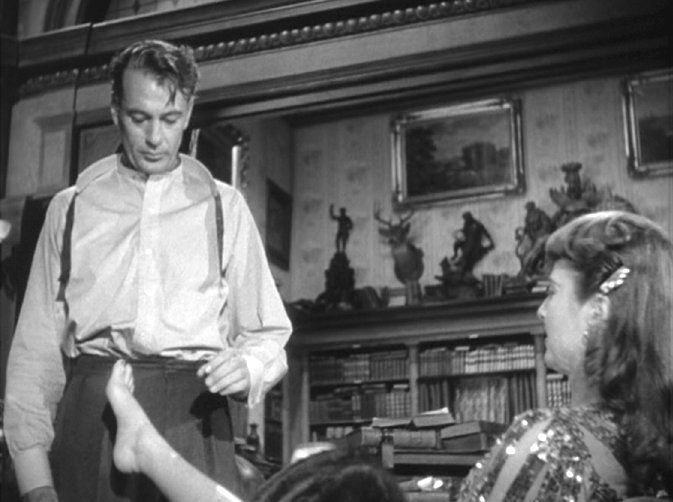 Stanwyck puts up her foot; Gary Cooper, as Prof. Bertram Potts, is nonplussed.