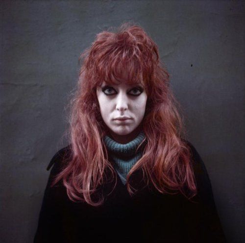 Myers with long red hair, wearing a green sweater