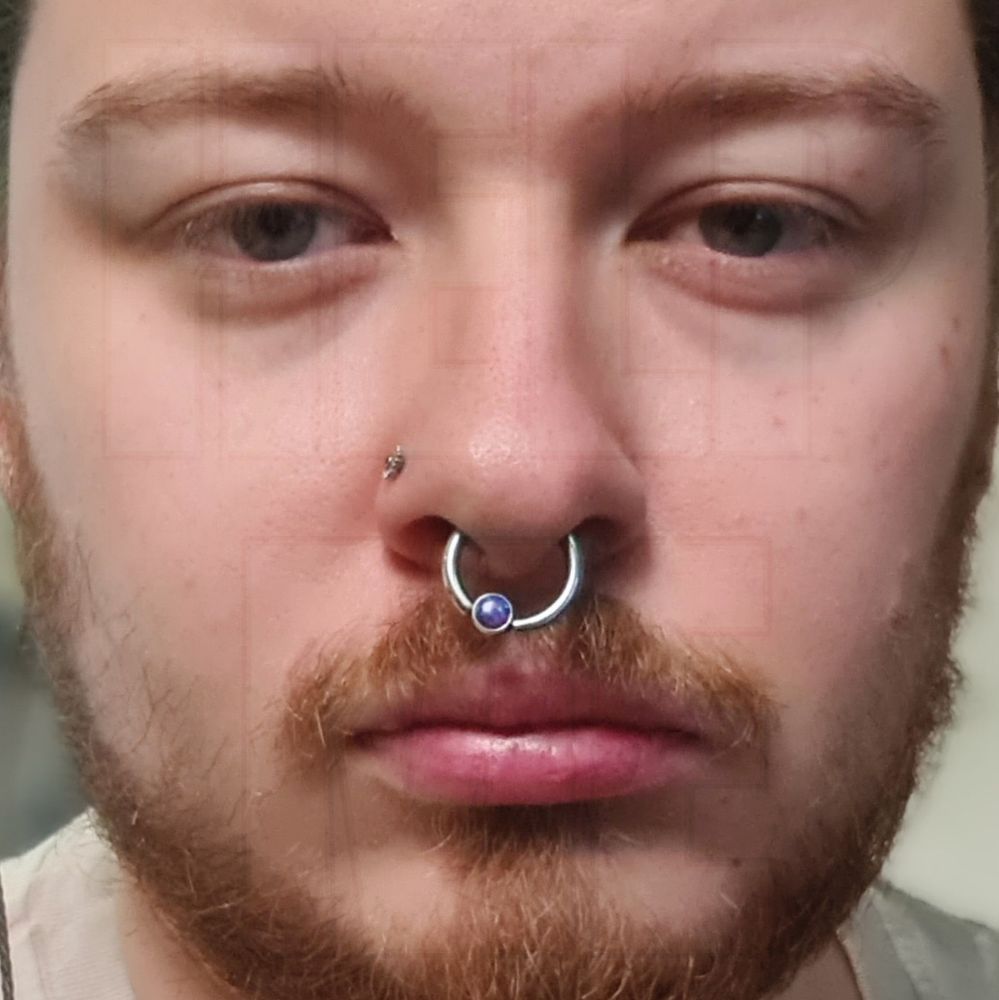 very zoomed in selfie of an exhausted looking white guy with a nostril and septum piercing