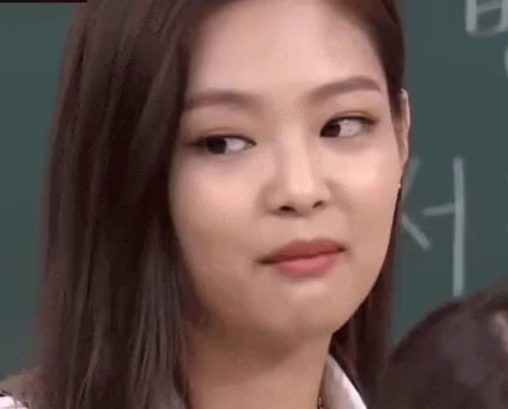 a close up of a woman 's face making a funny face in front of a blackboard .