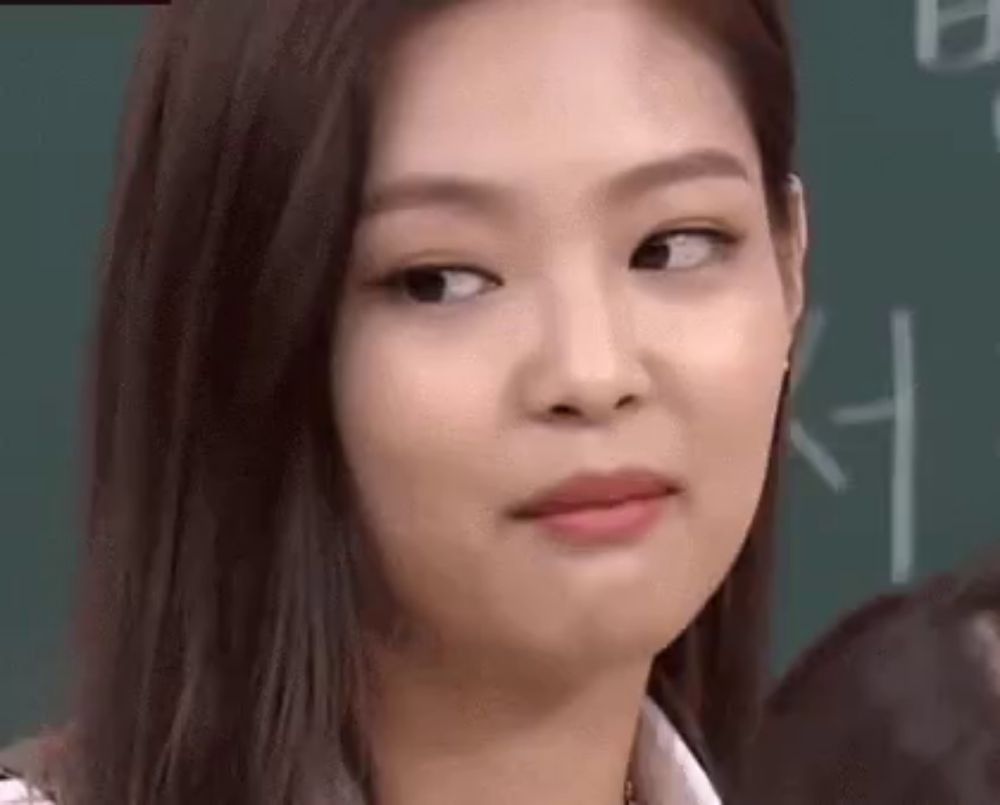 a close up of a woman 's face making a funny face in front of a blackboard .