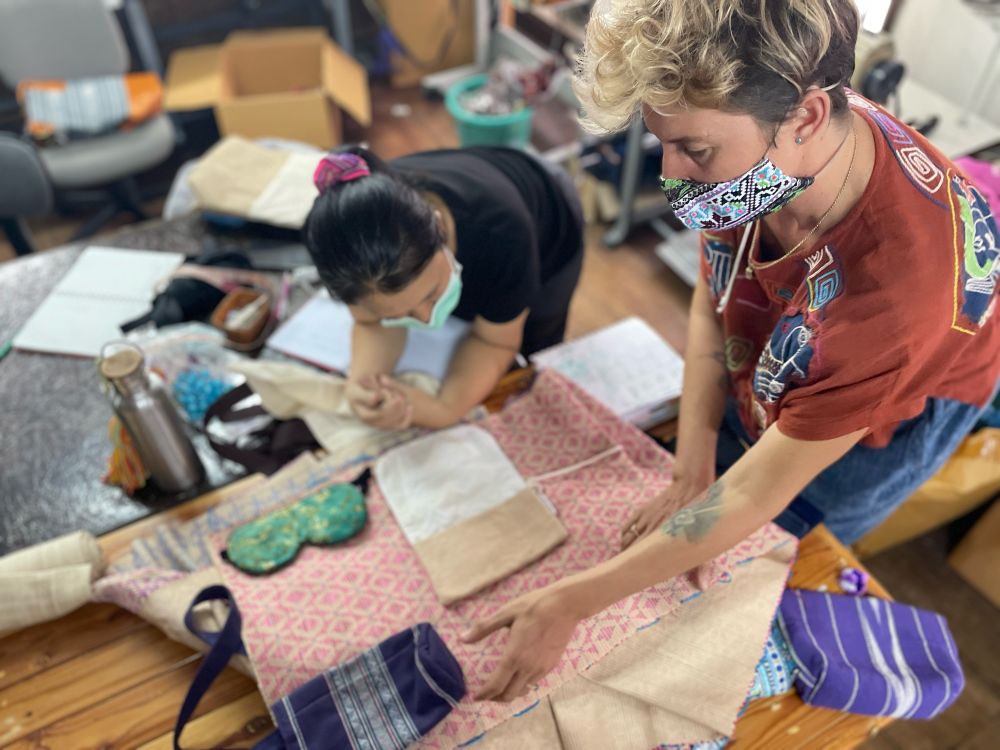Throwback to 2021, Kim and May in the work room hunched over a table to design the handwoven Lahu travel accessory collection after making a thousand face masks together in 2020. 