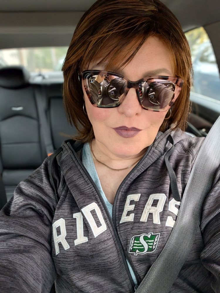 A selfie of Kelsey in her car. She's wearing mirrored sunglasses with heavy tortoiseshell frames.