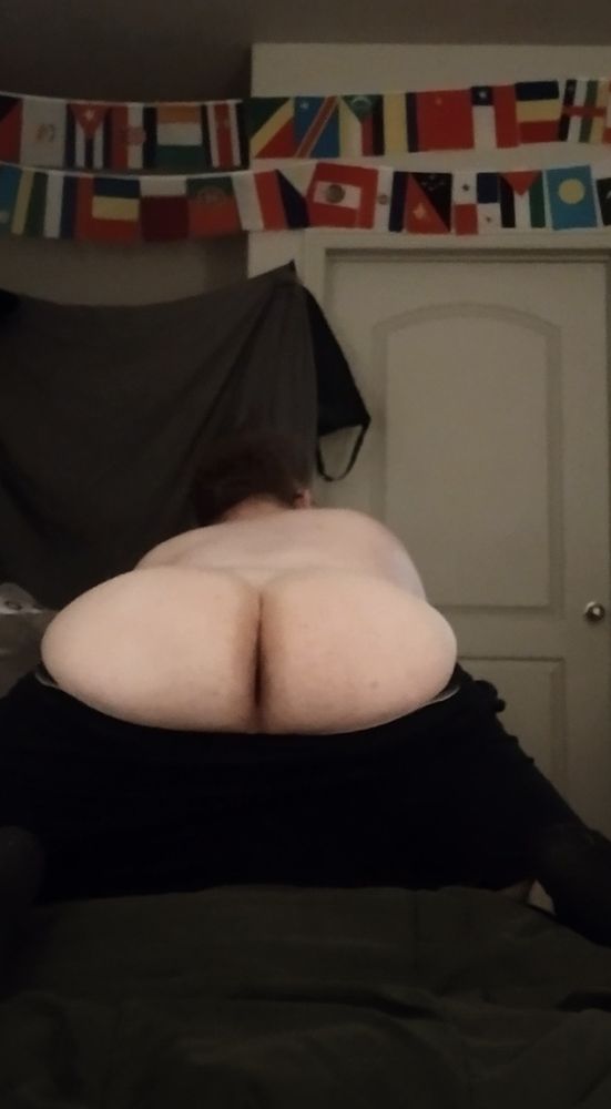 Just me bending over the couch with my ass hanging out of my shorts. My butt is rather wide. It may not be the most voluptuous of butts, but(t) it's all mine. I'm kneeling on my bed covered with a dark green comforter. In the background is a white door, a hanging grey sheet, and a number of flags. 