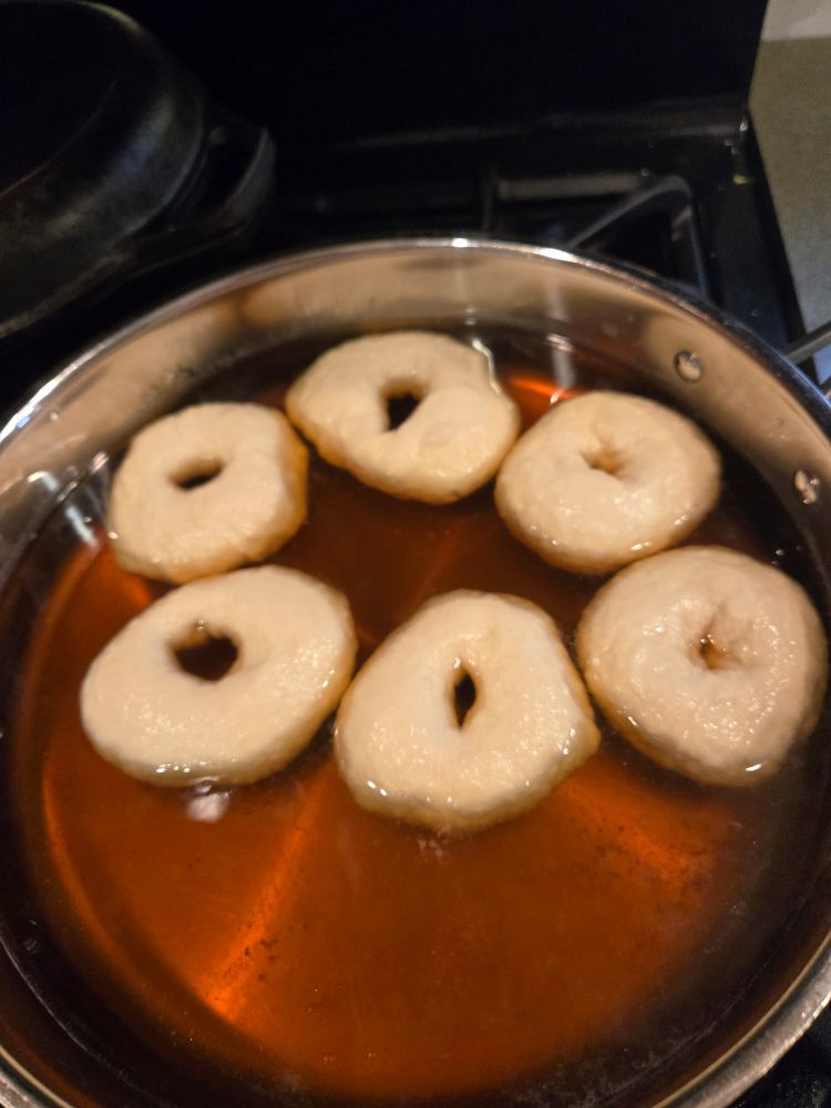 6 bagels boiling in brown liquid