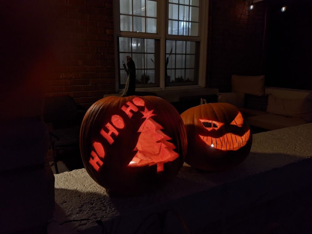 Two carved jack-o'-lanterns: one with a Christmas tree and "ho ho ho", and the other with a eyes and a big grin with toothpicks for teeth