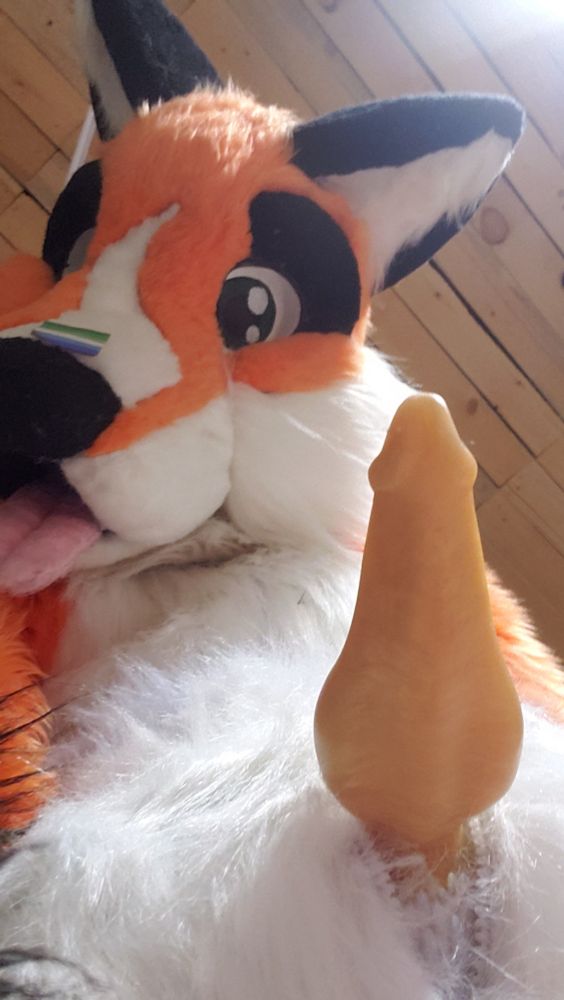 Orange fox fursuit, yellow knotted taper dildo poking out of the crotch, taken from below looking up, with the fursuit looking down at you expectingly~  