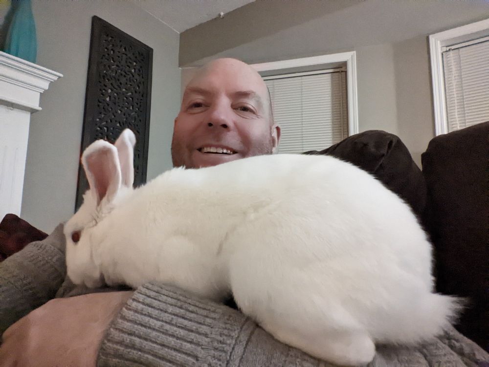 Aaron posting with his rabbit Milo crawling over him