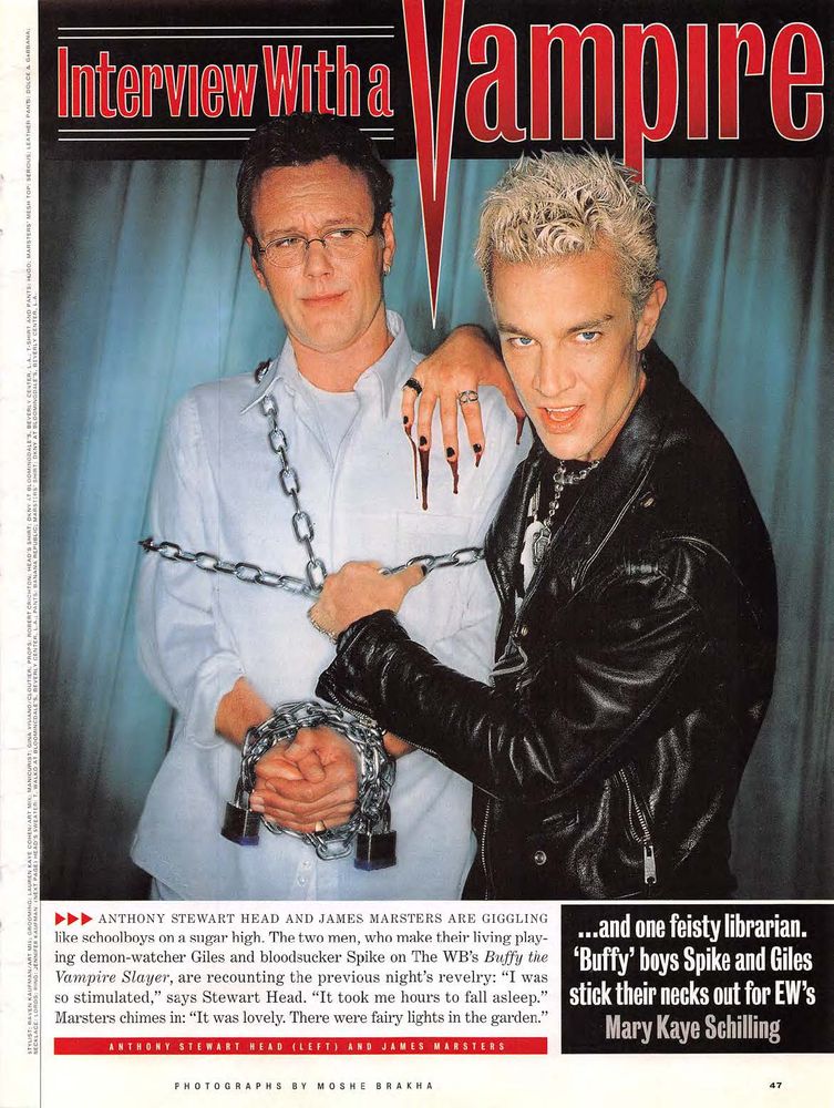 The image features two men standing close together. The man on the left is wearing glasses and a light blue shirt. His expression is neutral, and there is a chain loosely draped around his neck. The man on the right has short, spiky blonde hair and is dressed in a black leather jacket. He is looking directly at the camera with a dramatic expression, holding the chain between them. Behind them is a blue curtain. The scene has a humorous and light-hearted tone.

Transcribed Text:

Interview With a Vampire

ANTHONY STEWART HEAD AND JAMES MARSTERS ARE GIGGLING like schoolboys on a sugar high. The two men, who make their living playing demon-watcher Giles and bloodsucker Spike on The WB's Buffy the Vampire Slayer, are recounting the previous night's revelry: "I was so stimulated," says Stewart Head. "It took me hours to fall asleep." Marsters chimes in: "It was lovely. There were fairy lights in the garden."