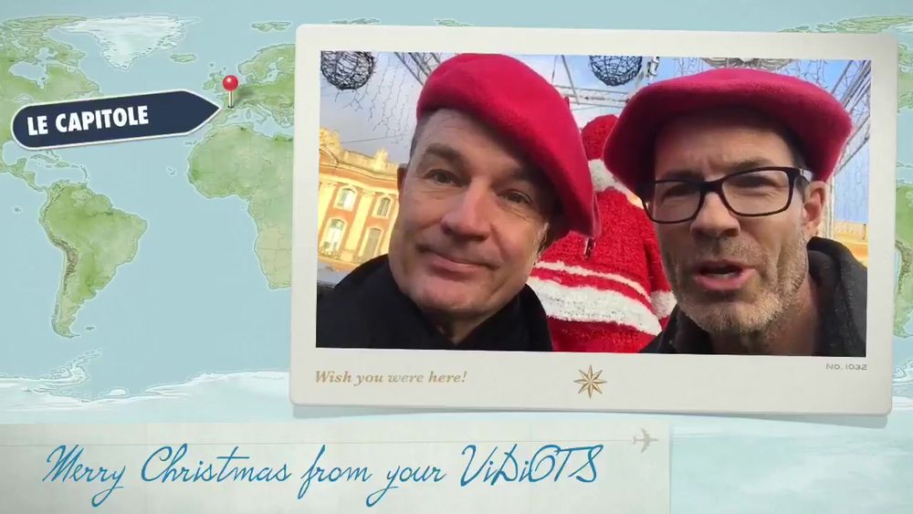 The image features a postcard-style overlay with a light beige frame surrounding a photograph of two men wearing red berets and winter clothing. They are outdoors, with Christmas decorations and a building visible in the background. The frame is set against a backdrop of a world map showing part of Europe, where a location is marked with a pin and label saying "Le Capitole." Below the frame is a handwritten-style message. The postcard has a vintage aesthetic.
