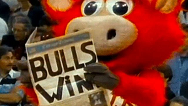 a bull mascot is holding a newspaper that says " bulls win "