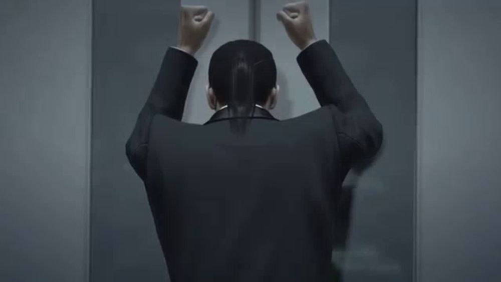 a man in a suit is leaning against a wall with his head down .