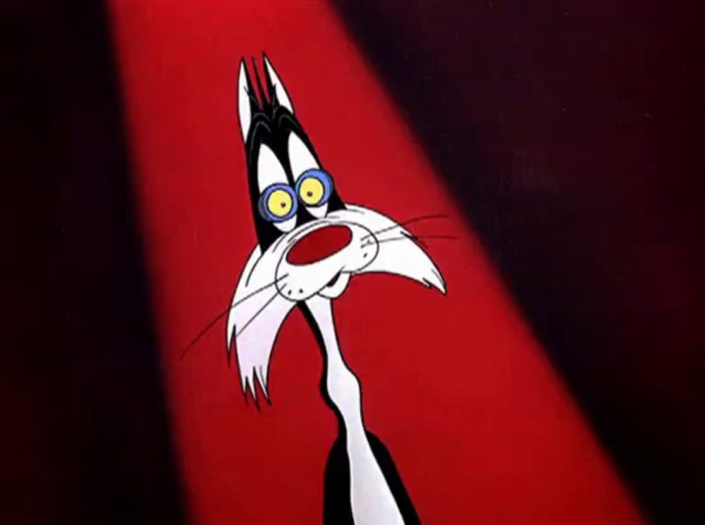 a black and white cartoon cat with blue eyes is standing in front of a red light .