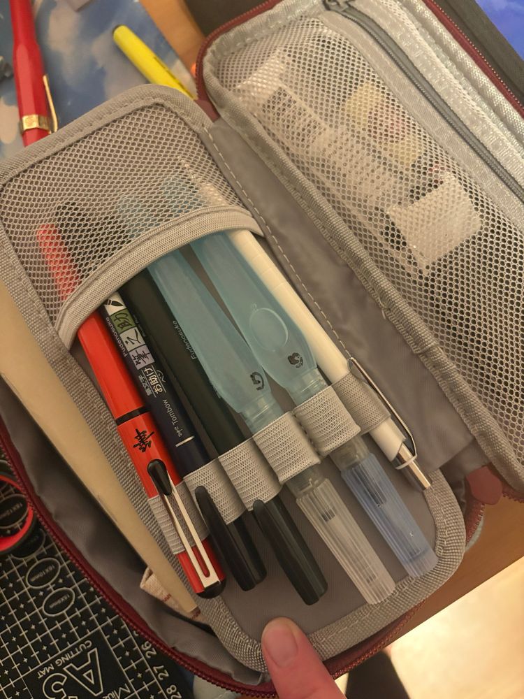 A photo of the travel art kit I packed. This picture shows two water brushes, a  mechanical pencil, a pentel pocket brush and two fudenosuke pens.
