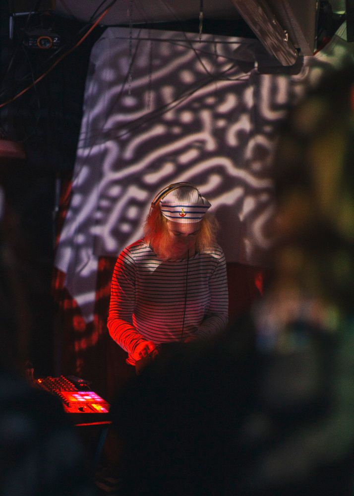 A woman in a sailor outfit playing electronic musical instruments
