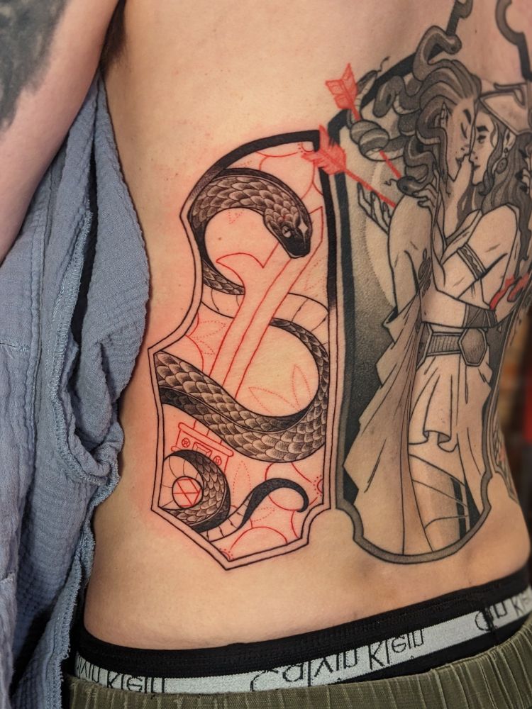 A close up of a fresh tattoo of a snake wrapped around Perseus's sword. 