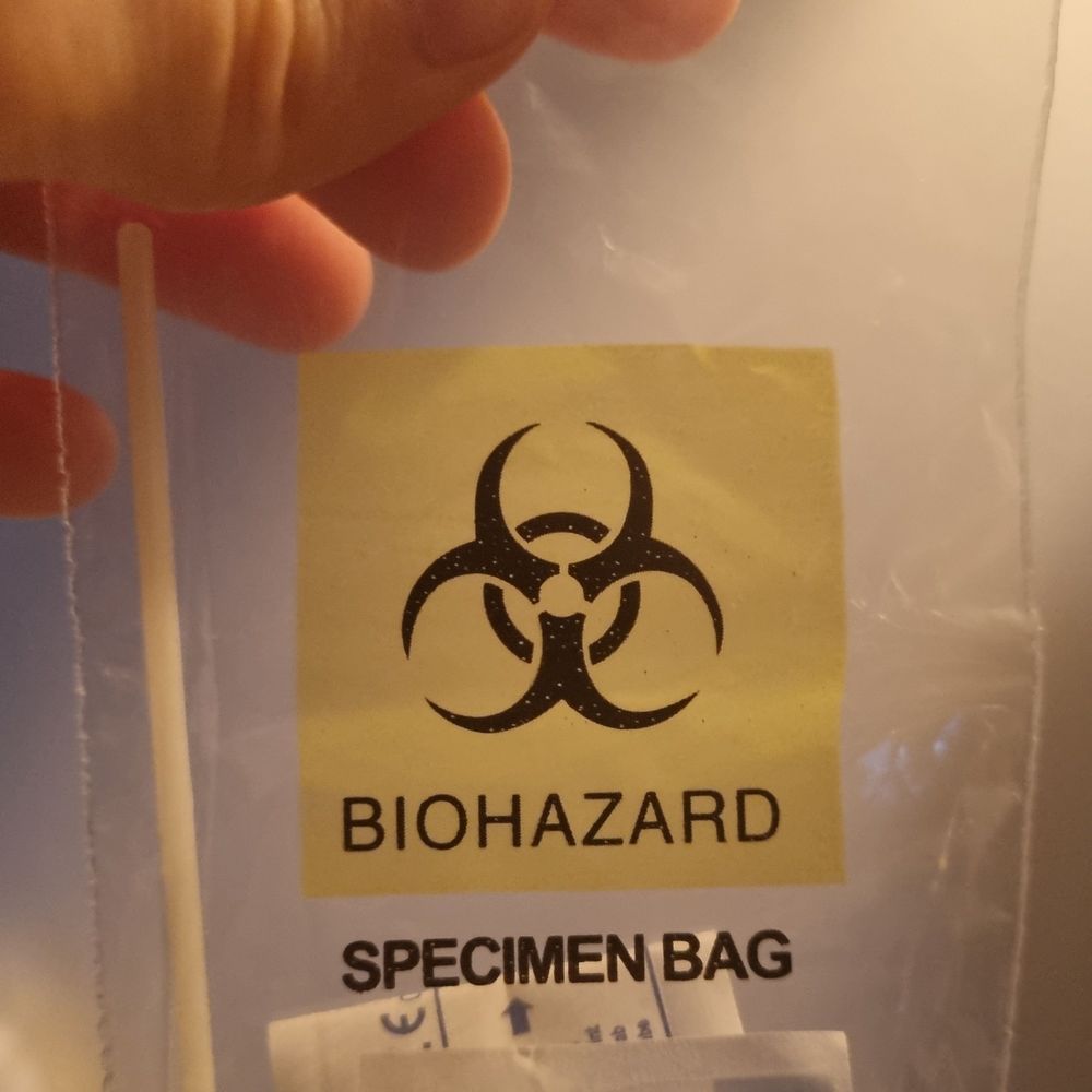 Corona-Test-Tüte mit dem Biohazard-Logo drauf.