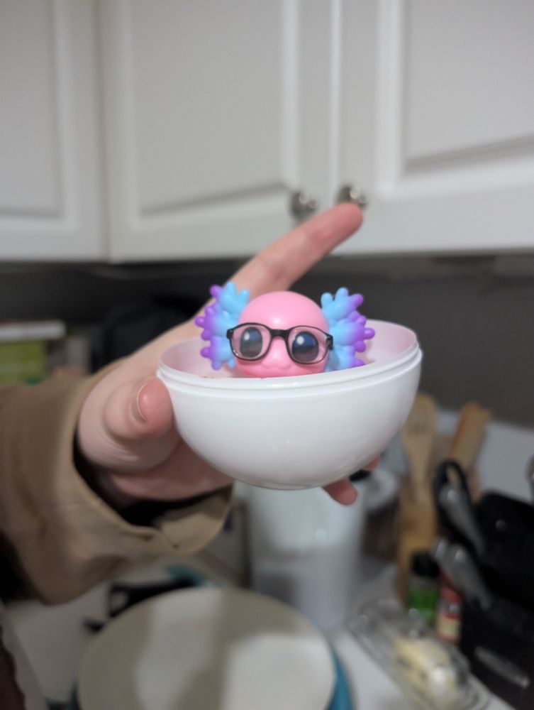 Reed A'Lotl sits peeking over half of a sphere