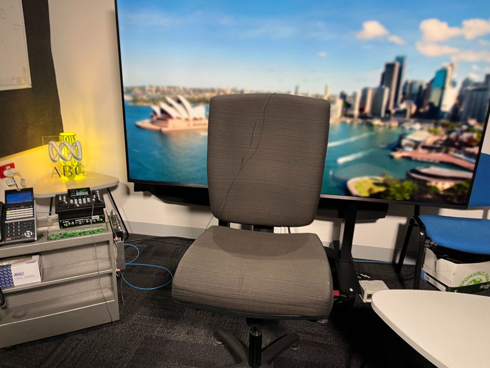 An empty seat in the ABC Ultimo studio which is used for live crosses to another TV studio. In the background is an image of Sydney harbour which forms a backdrop for interviews. 