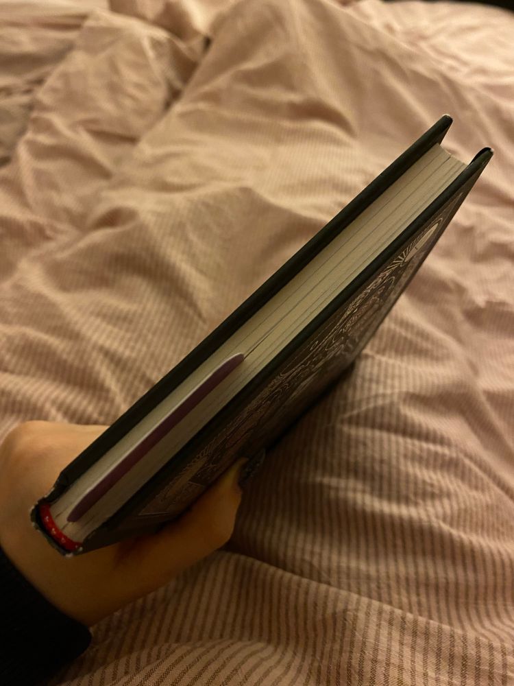 A sideway view of the top of a slim booklet with a bookmark sticking out at the top about halfway in the middle between the pages.