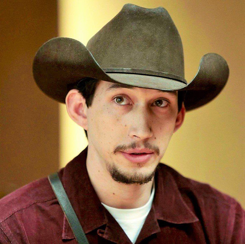 Adam Driver - in burgundy shirt and cowboy hat - listening intently (taken from the film Inside Llewyn Davis). 