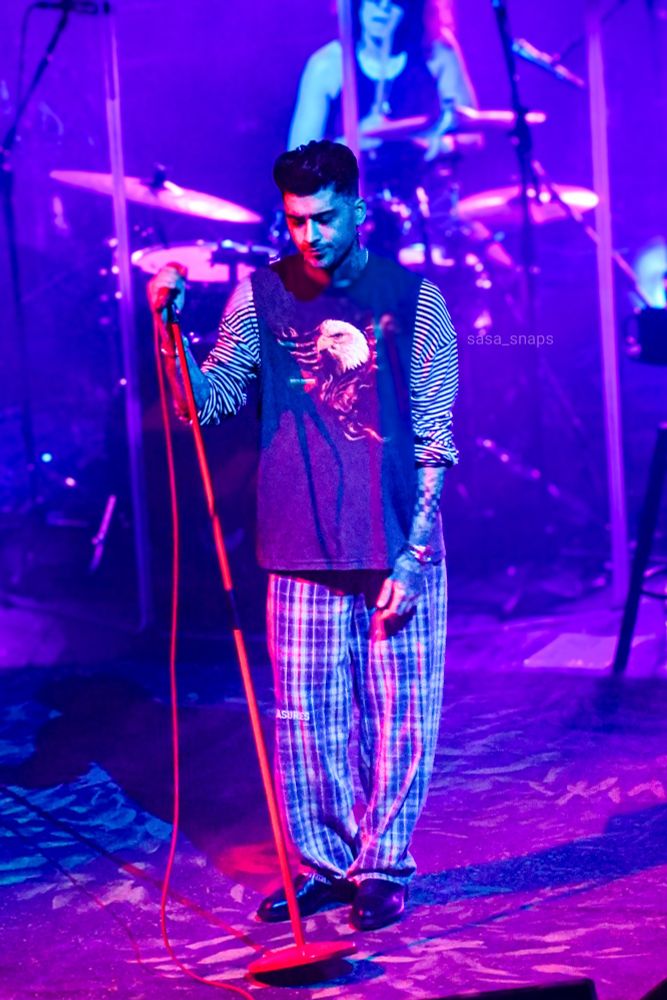 Zayn on stage bathed in red and blue lights.