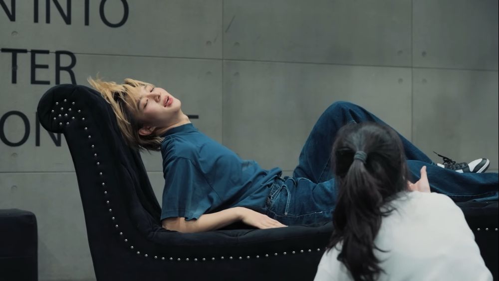 NuNew with his hair tossed back reclining on the couch from Stuck With U during rehearsal