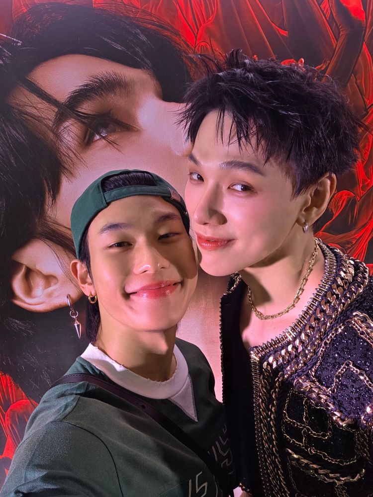 Selfie of DaouOffroad in front of a poster of Jeff Satur's face at his concert. Offroad is wearing a green backwards baseball baseball hat and matching shirt and dish is wearing a black and gold Chanel-looking jacket