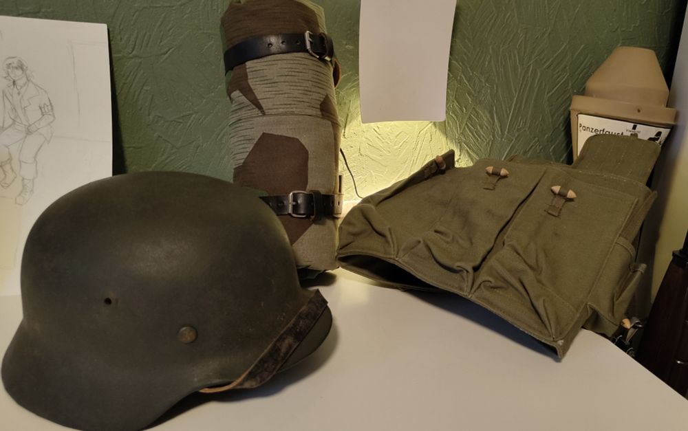 An M40 Helmet, Rolled up Zeltbahn, and Type 56 Chest Rig laid out on a table.