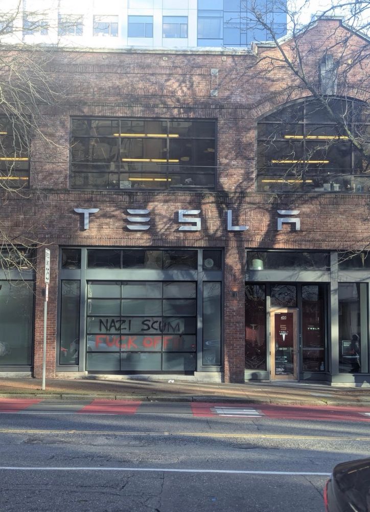 Graffiti on a Tesla store front in Seattle that reads, “Nazi scum. Fuck off.”