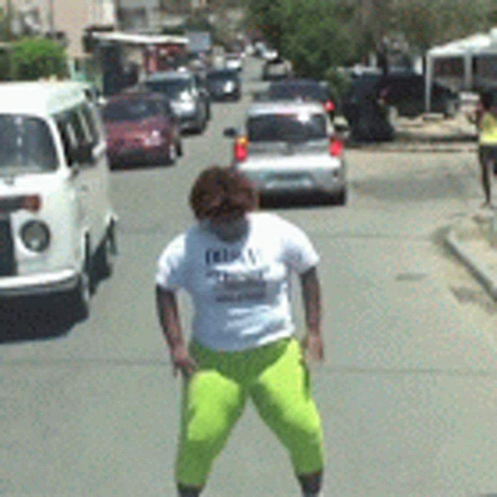 a woman in a white shirt and neon yellow shorts is standing on a busy street