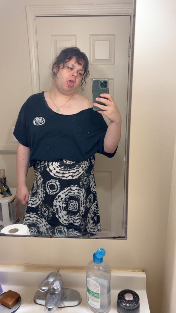 Mirror selfie of user wearing black shirt and black and white skirt.