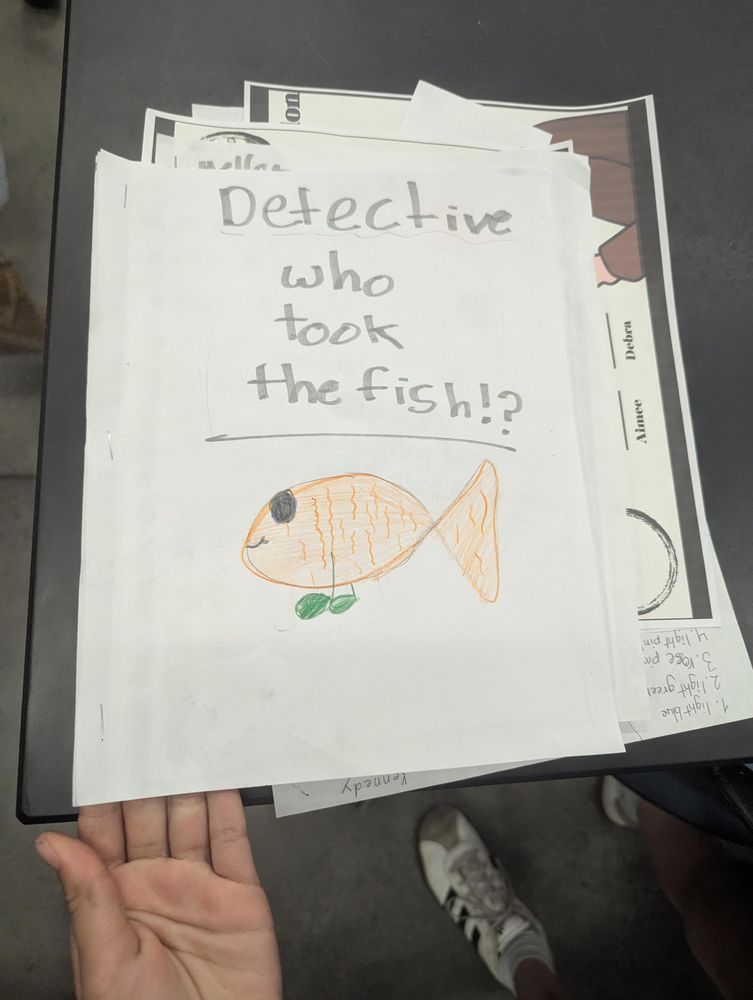 A notebook with a crayon picture of a fish drawn on it and titled "Detective who took the fish"